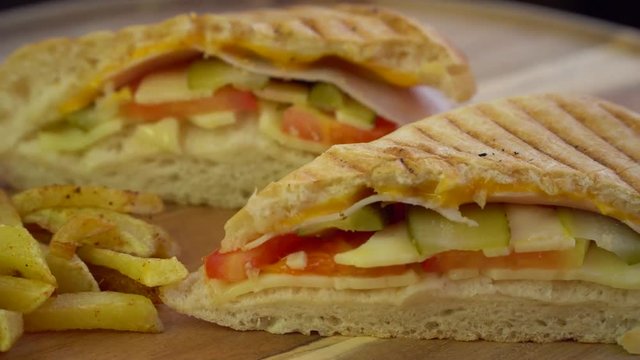 Sandwich toast grilled with cheese and vegetables, ham,  served with french fries, rotating