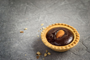 Small Chocolate Tart with almond on a gray stone background, spa