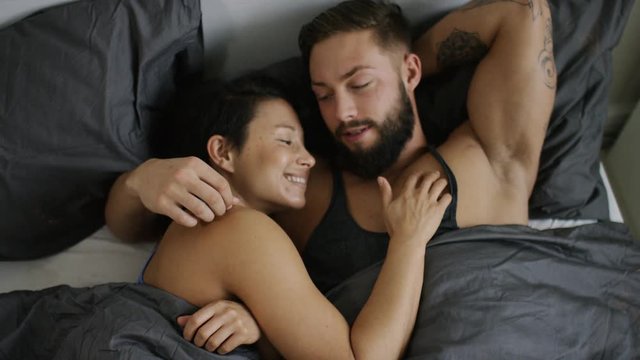 4K Happy couple in bed talking, share a kiss