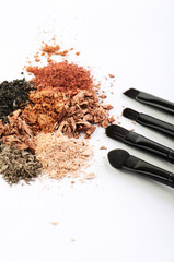 four makeup brushes and crumbled eyeshadow of different colors
