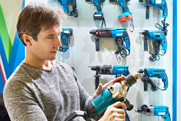Man shopping for hammer drill in hardware store