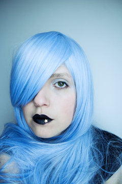 Retrato artístico de una chica joven con el pelo azul y los labios pintados de negro 