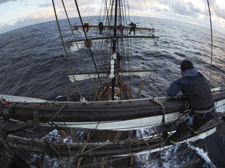sailors aloft furling sails on a traditional tallship