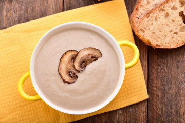 Mushroom cream soup on yellow napkin. Wooden table. Top view.