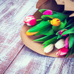 the bouquet of tulips is wrapped in a paper isolated on a wood background