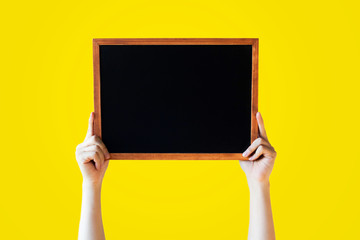 Human Hands Holding Empty Blank Black Board Over Yellow Background - Ready for adding your text here 
