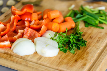 Obraz na płótnie Canvas Onion, Carrots, Bell Peppers, Garlic And Parsley Raw Vegetables Ingredients On Wood
