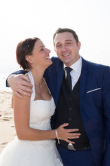 Lovely married couple smiling and hugging on the beach