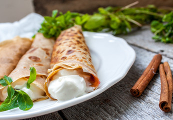 Russian thin pancakes with butter, cheese, jam, mint on a napkin on a wooden background.  Love for a healthy sweet  food concept