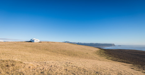 Fototapeta na wymiar Lonely house on grass hill with blue sky in southern Iceland