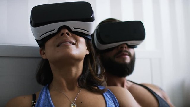 4K Couple in bed using virtual reality headsets in unison