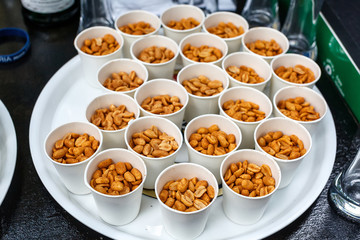 Paper cup of fresh roasted salted peanuts or groundnuts on an table or bar counter