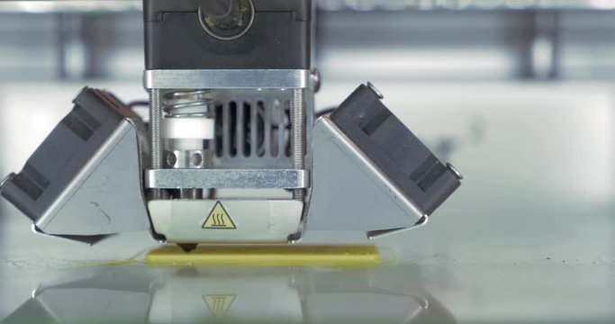 Front close-up view of 3d printer in process It makes pieces for equipment with yellow plastic