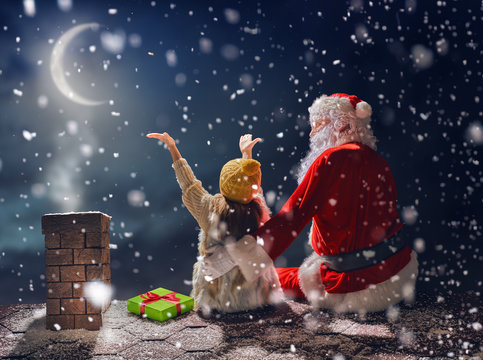 girl and Santa Claus sitting on the roof