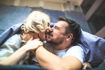 Young couple fooling around in bed, close-up, emotion, a lot of laughter and fun.covered with a blanket