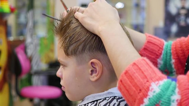 haircut of a child with scissors in the barbershop