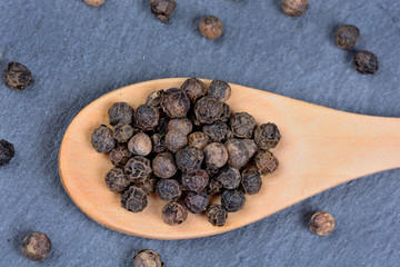 Wooden spoon with black peppercorns