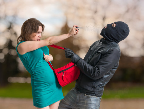 Self defense concept. Young woman is spraying with pepper spray.