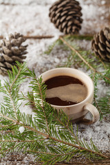 mug with a hot drink and with a fir-cone on a wooden stump in th