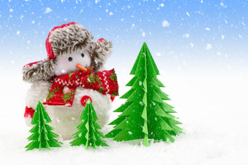 Christmas background, snowman with paper trees in the snow