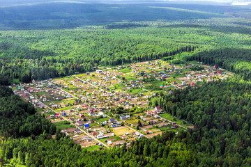 Fototapeta na wymiar The cozy little village in the middle of the taiga forest. Airview