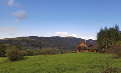 Fototapeta na wymiar Traditional wooden mountain house on green field in Bieszczady, Poland