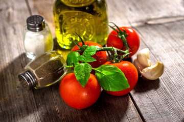 Olive oil, tomato and herbs on rustic wooden table
