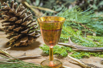 Beautiful glass of pink wine, big pine cone and deer antlers on rustic wooden table 