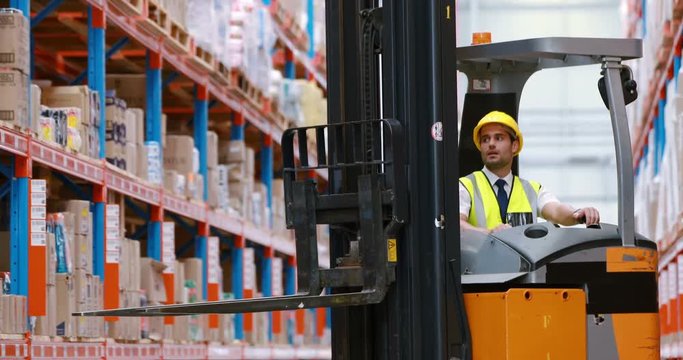 Male warehouse worker using forklift truck