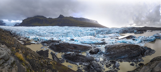 Svinafellsjokull glacier tongue in winter, blue ice covered by snow and mountain peaks, Iceland