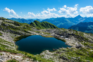 Naklejka na ściany i meble Calm lake reflecting blue sky in the Alps