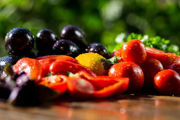 Close-up of fresh, ripe tomatoes, eggplant, sweet red pepper and parsley on wood background.Group of vegetables. Red and yellow tomatoes,pepper, eggplant and parsley in drops of water 