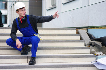 Mann auf der Baustelle in Arbeitskleidung zeigt auf die Baustelle