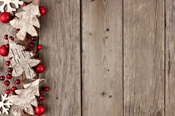 Rustic Christmas side border with wood ornaments and berries on an aged wood background