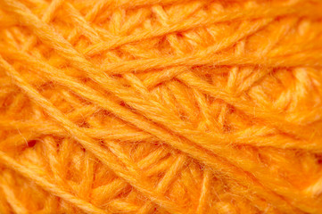 Woolen yarn ball, skein of tangled orange sewing threads, selective focus 