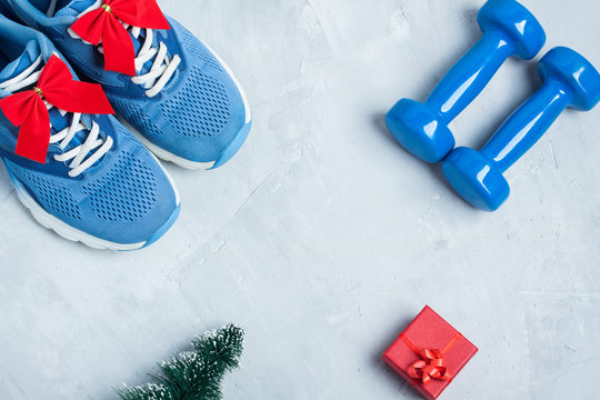 Christmas sport composition with shoes, dumbbells and red gift b