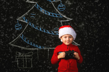 boy with retro camera in hands on a Christmas background . in the Santa hat