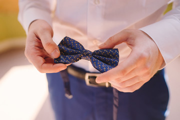 Men's fashion and style. Caucasian guy in suit holding bow tie in his hands