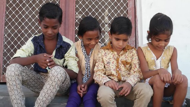 Indian kids with their heads down but still smiling smugly, handheld 