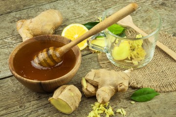 Fototapeta premium Preparing ginger tea against influenza. Traditional treatment for colds. Ginger, lemon and honey bowl on wooden table. Rustic wooden background. Home Pharmacy. 