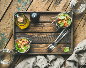 Homemade glass jar quinoa salad with cherry and sun-dried tomatoes, avocado, basil in wooden box...