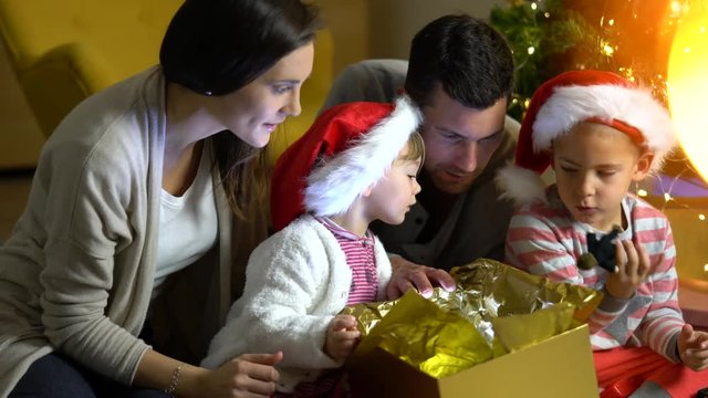 Parents with kids opening gift on Christmas celebration