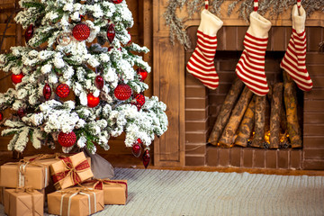 Fototapeta premium Beautiful holiday decorated home room with Christmas tree, gifts under it and red Christmas socks.