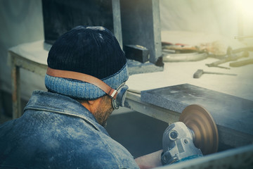Obraz premium A worker sculptor cuts the granite.