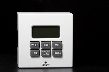 White plug-in timer for electrical items. Black background. Mainly used for turning lamps and...