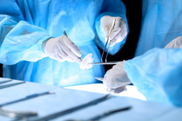 Medical team performing operation. Group of surgeon is working in operating theatre toned in blue