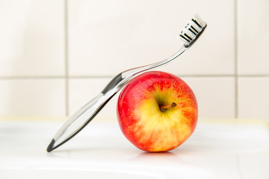 Black and transparent toothbrush with an apple.