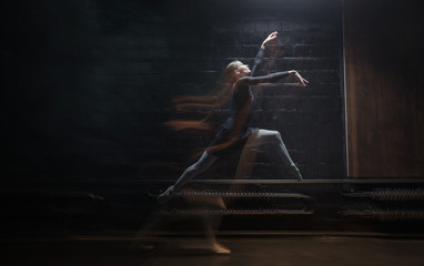 Obraz na płótnie Canvas Young gymnast jumping on the dark background