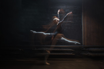 Delighted gymnast jumping on the dark background