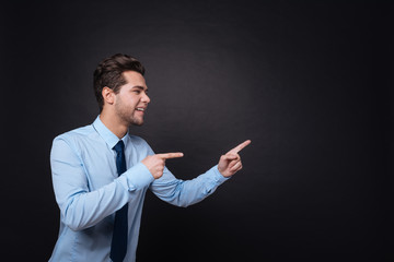 Cheerful businessman pointing aside.